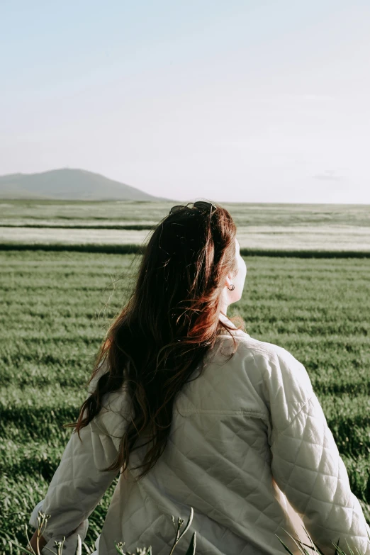 woman in field looking at horizon of land and hills