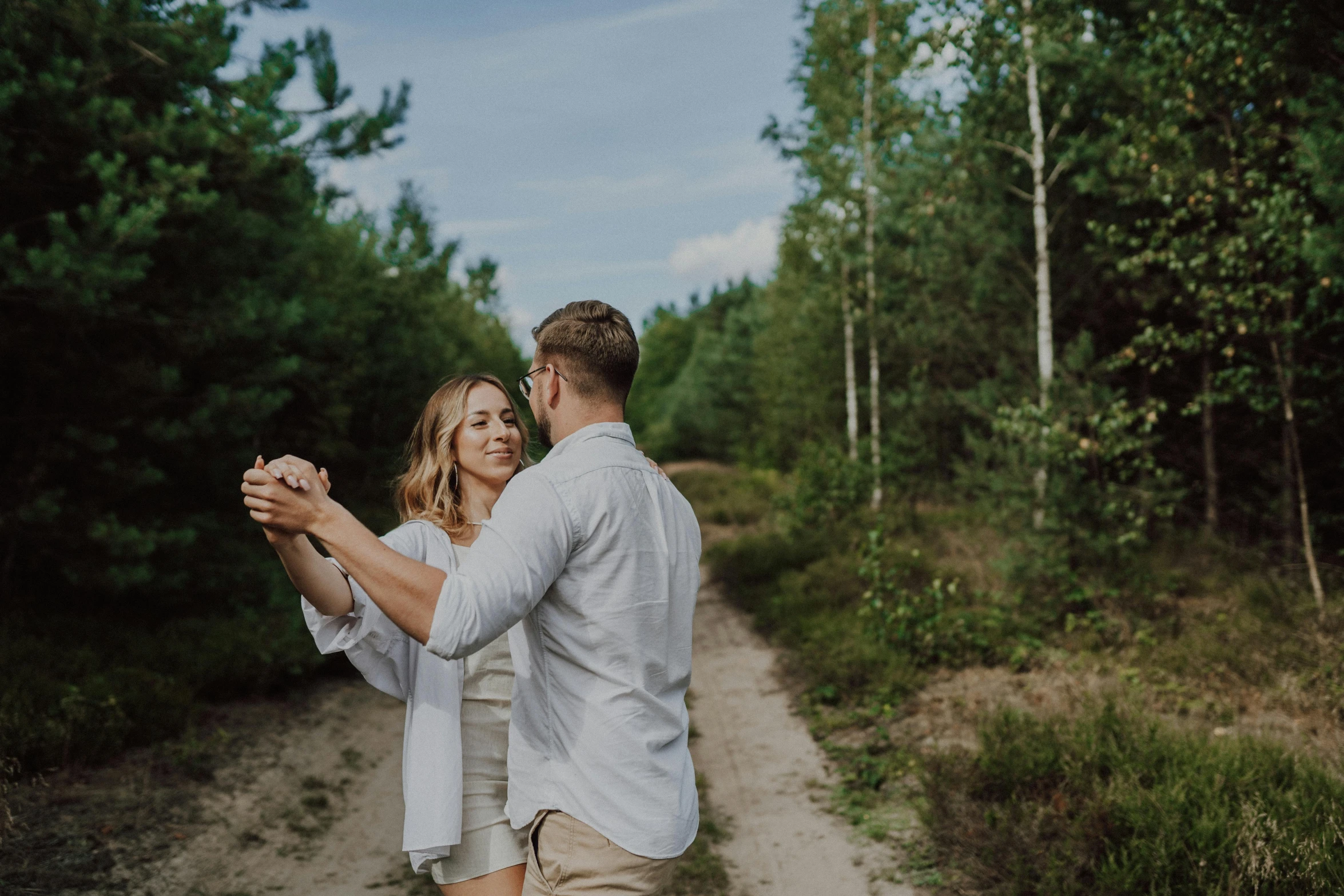 a man and woman walking through the woods