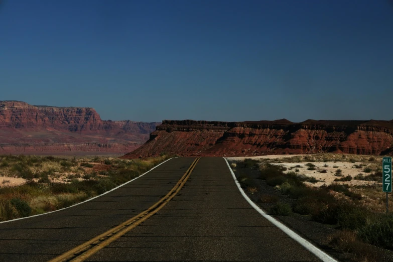 a car drives down a road near some red mountains