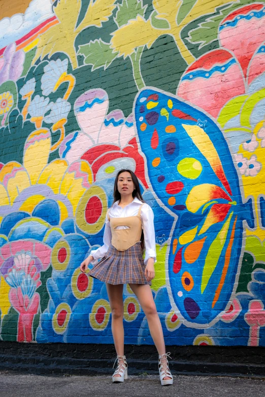 the woman is posing against a mural on the building