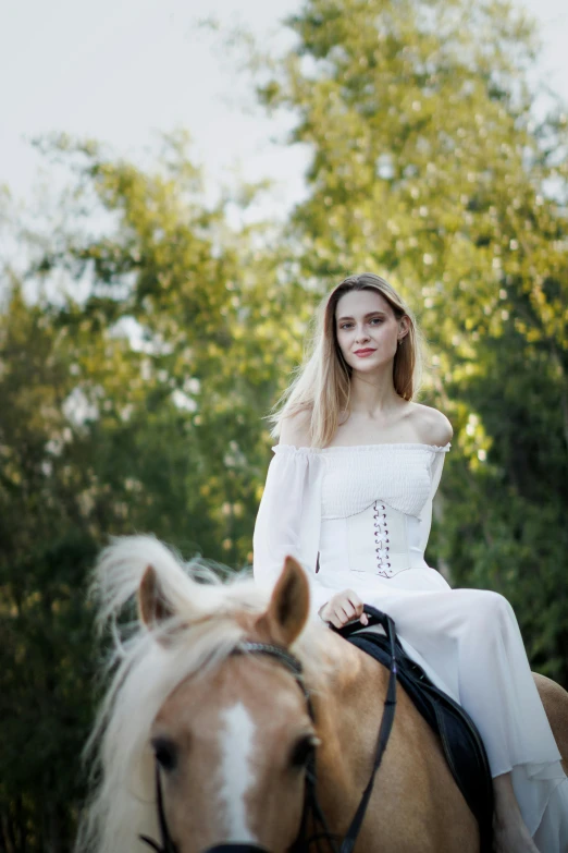 a woman in a white dress riding on a horse