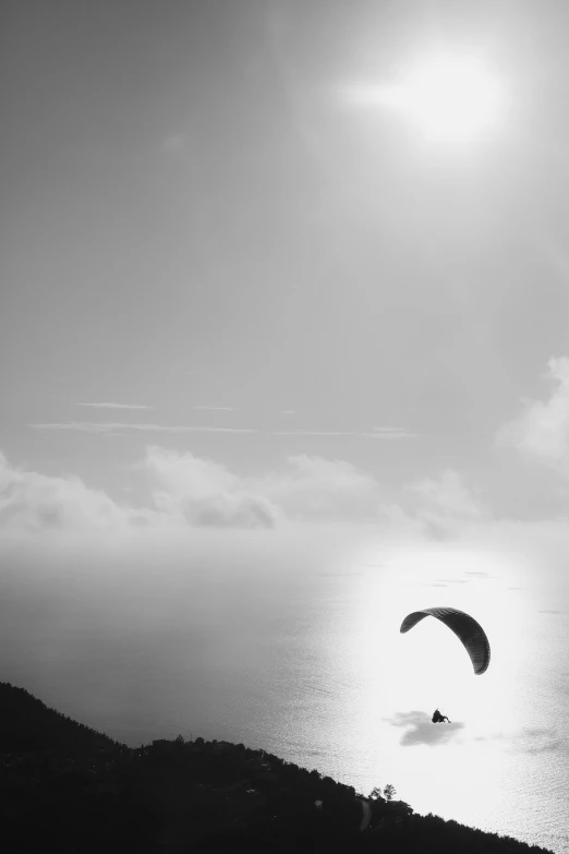 person on water in parachute with sun overhead