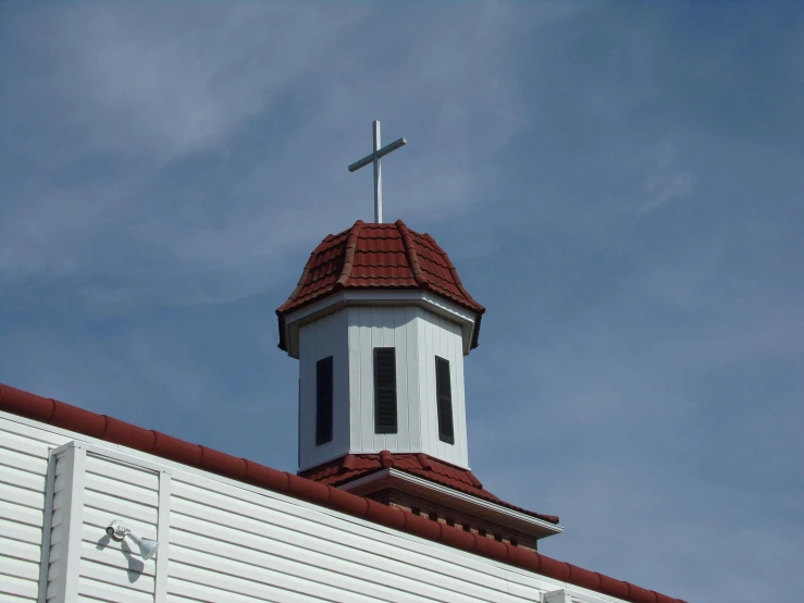 a white church steeple with a cross on top