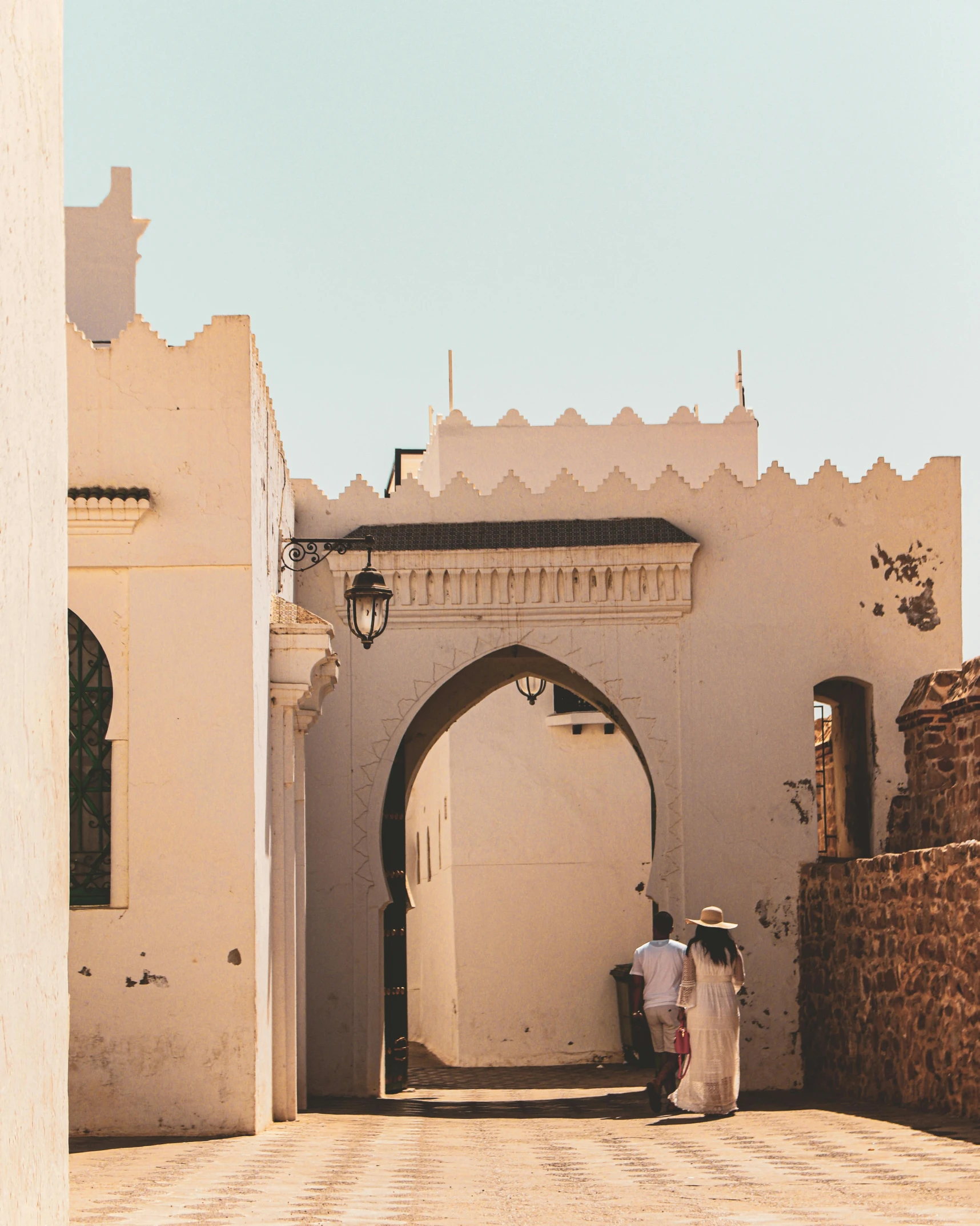 two people wearing traditional clothing standing outside of an archway