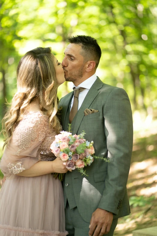 a beautiful woman kissing a man in a tuxedo