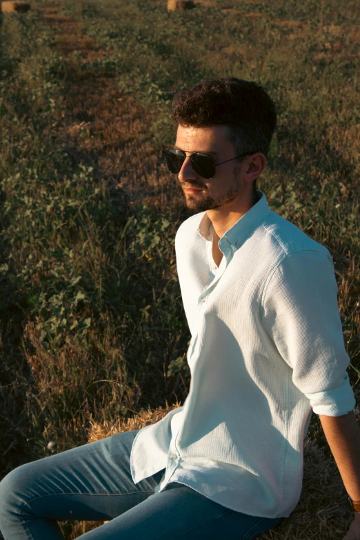 man with sunglasses sitting on ground and staring