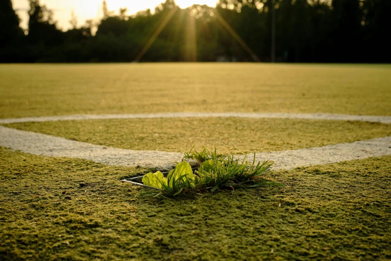 a sun glaring over a baseball field in the distance