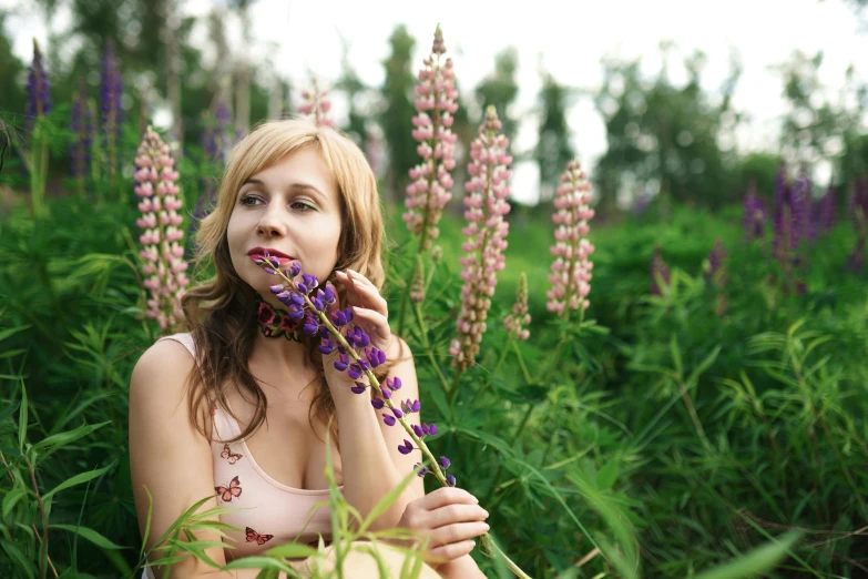 a young woman wearing a  and with her eyes closed posing in the middle of the grass