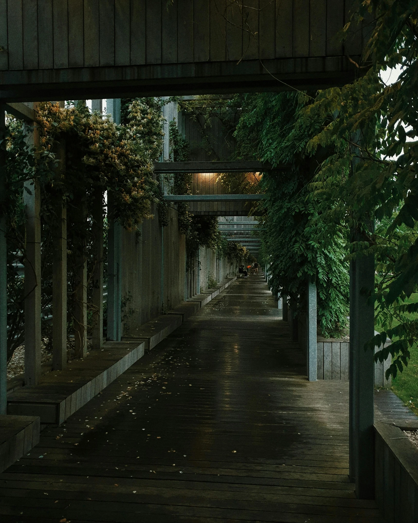 an old alley with a clock on one side and wooden walkway at the other