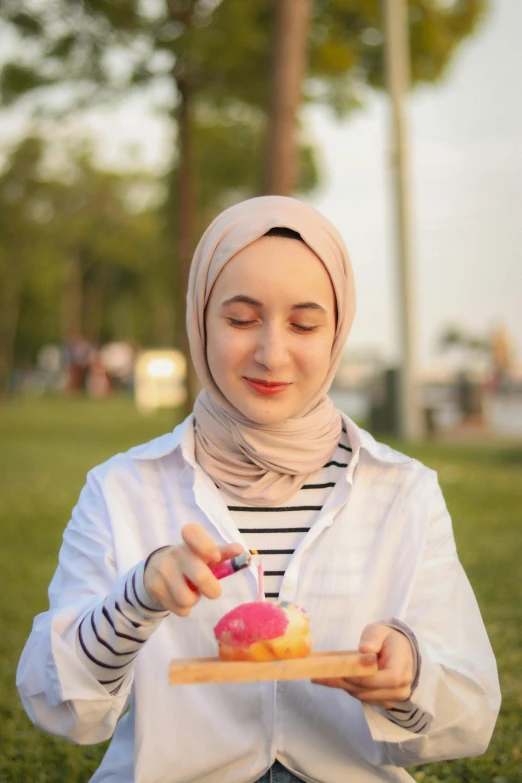 a woman standing outside in a park holding a plate of food