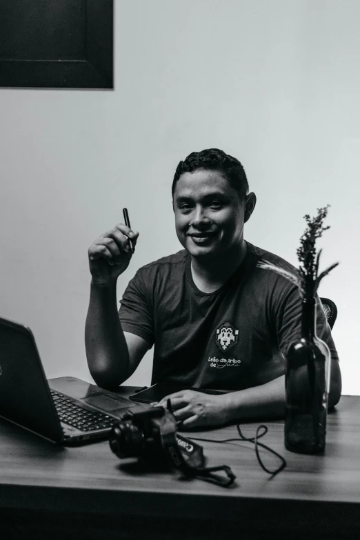 a man sitting in front of a laptop computer smiling