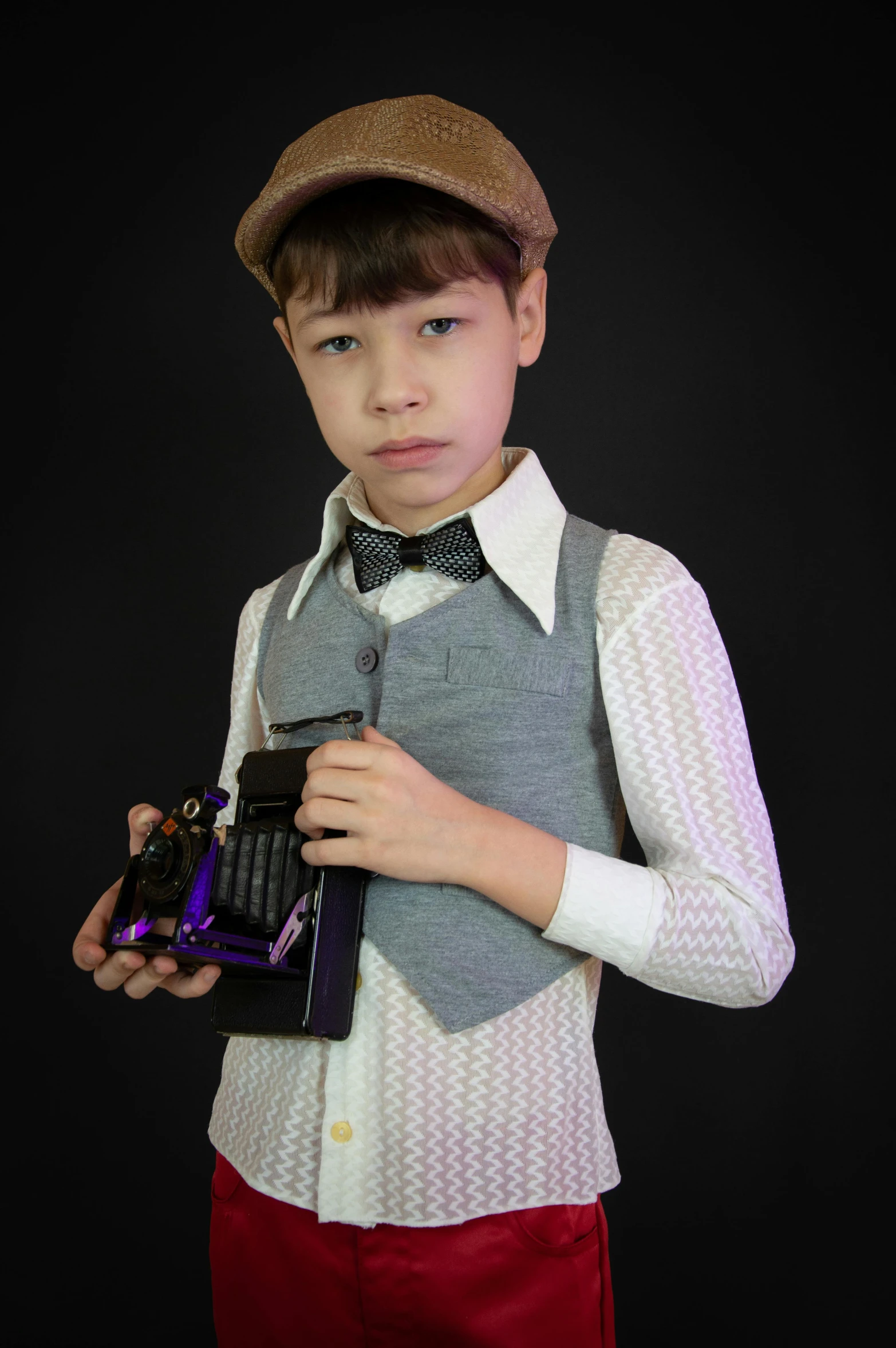 a  wearing a hat and bow tie holding a small toy