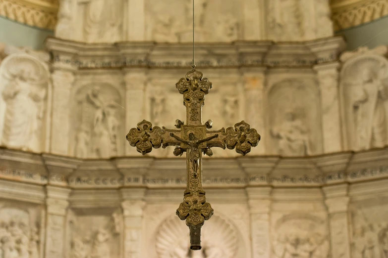 ornate gilded cross hanging from the ceiling with light