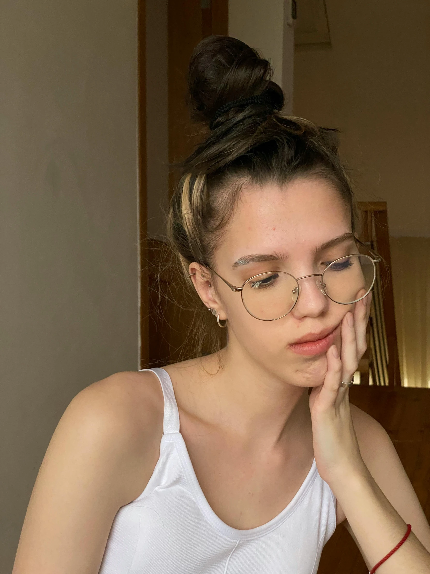 a young woman wearing glasses looks at her cell phone