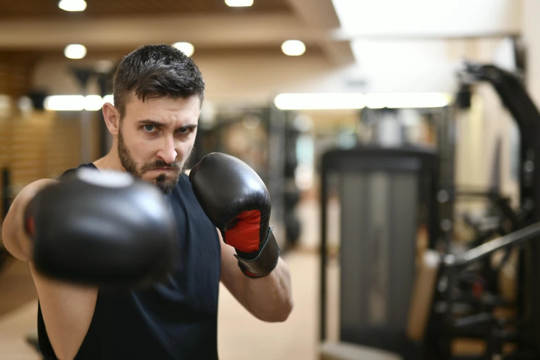 man with beard and tattoos practicing boxing in a gym