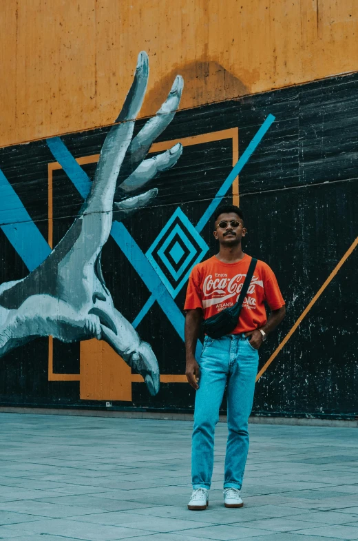 a man standing in front of a wall with a mural behind it