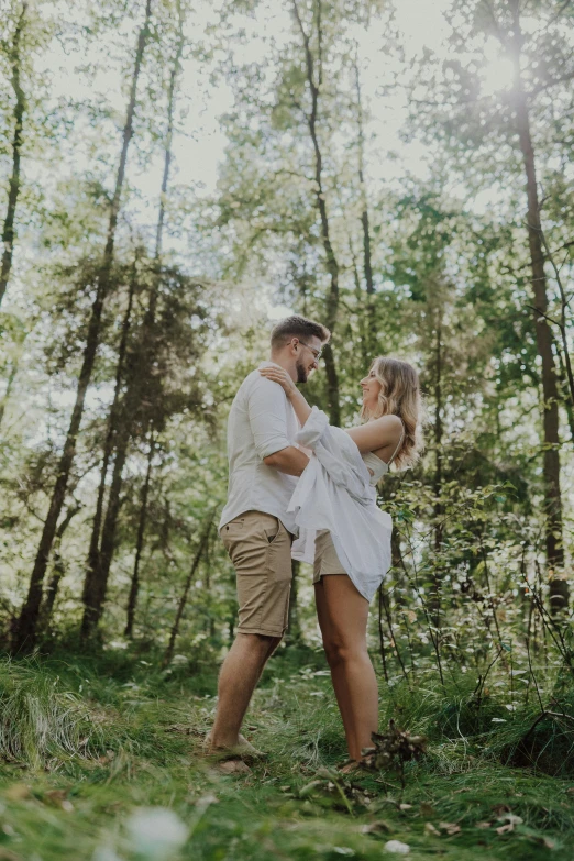 a man and a woman holding each other in a forest