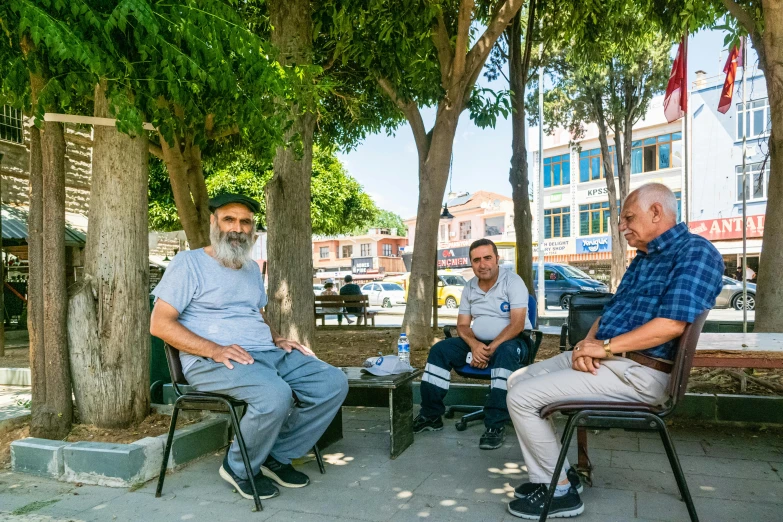 four people are sitting around near trees in the park