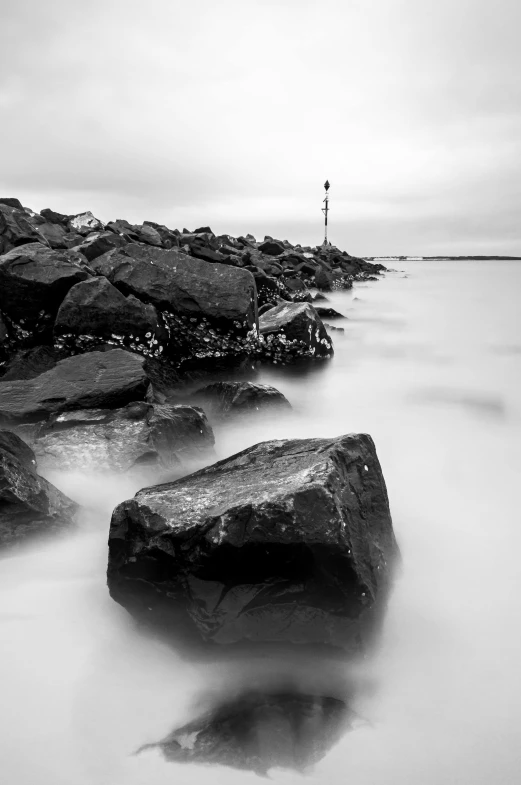 rocks are standing out in the water as a light house sits on top of it