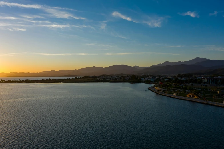 a bright sun rises above the mountains near a lake