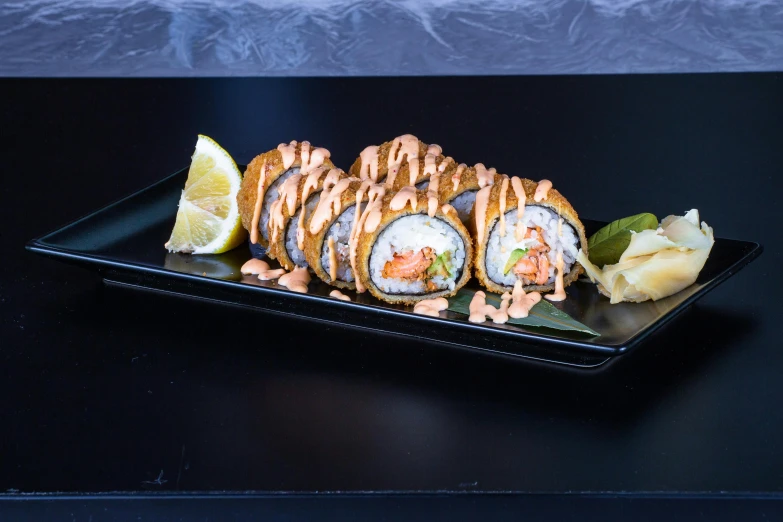 a tray with sushi and a lemon wedge