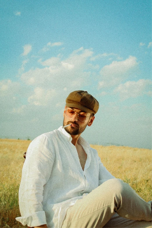 a man with a hat and white pants sits on the grass