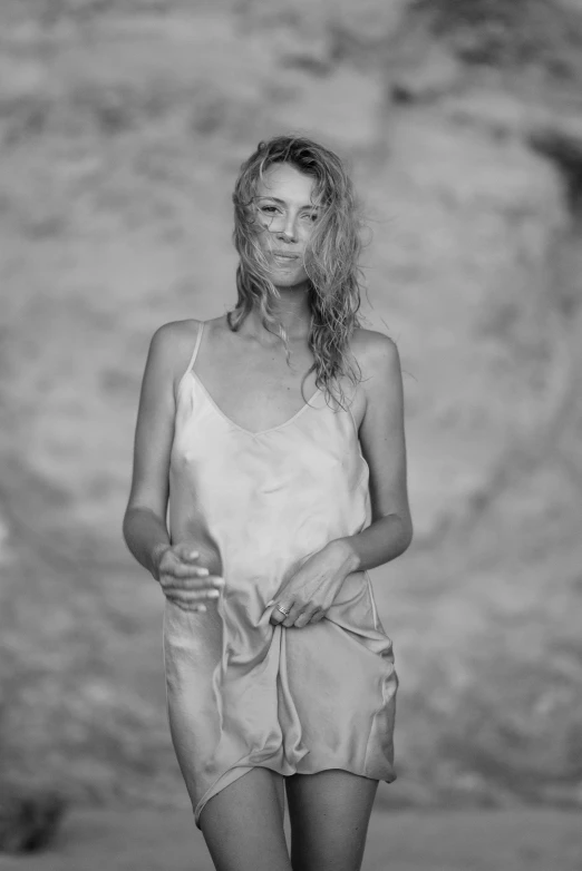 a young woman stands on the beach with her arms folded out