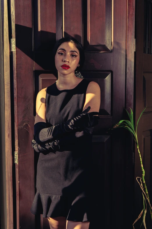 a woman standing by a door and a plant