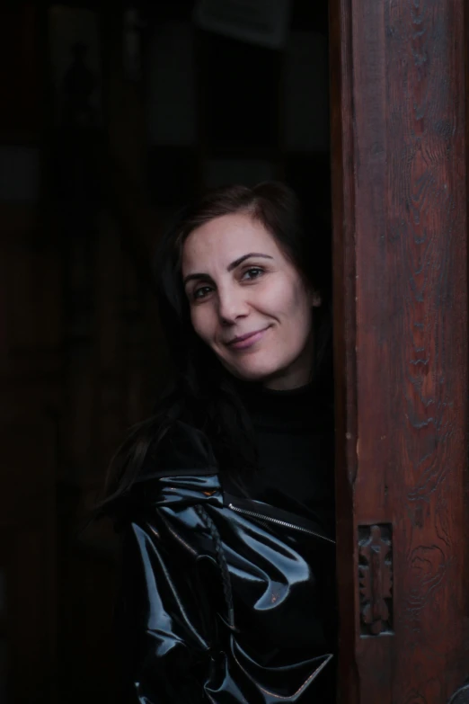 woman wearing black leather jacket leaning out the window