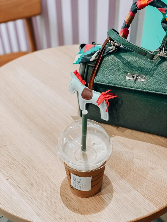 a green coffee cup and green handbag sitting on a table