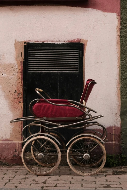 a red carriage is sitting outside near a doorway