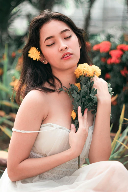 woman wearing dress sitting in garden with yellow flower