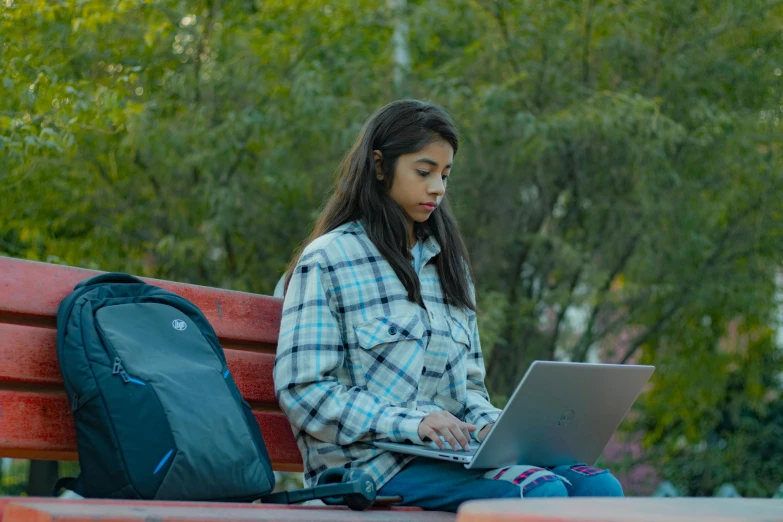 a woman is sitting outside using a laptop