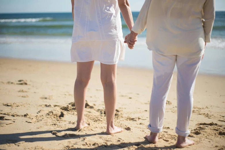 two people holding hands walking along the beach