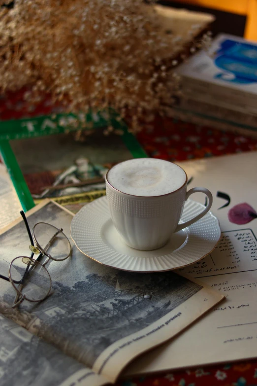 a cup of coffee with eye glasses on top of a magazine