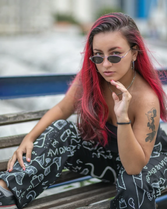 a woman sitting on top of a wooden bench wearing glasses