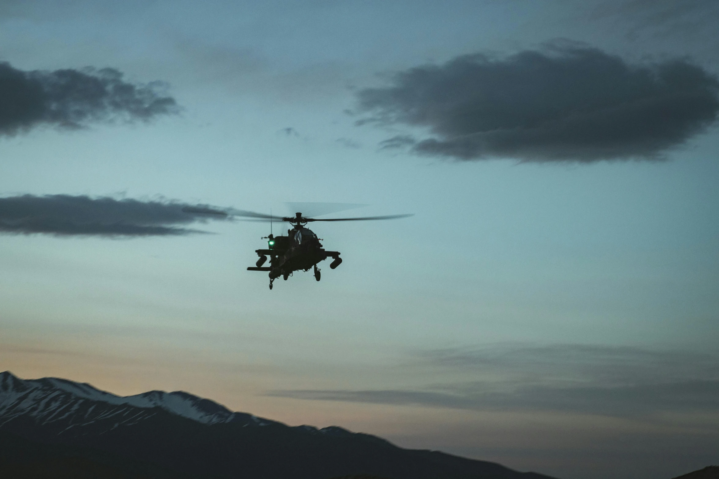 a helicopter flying over mountains during a dusk sky