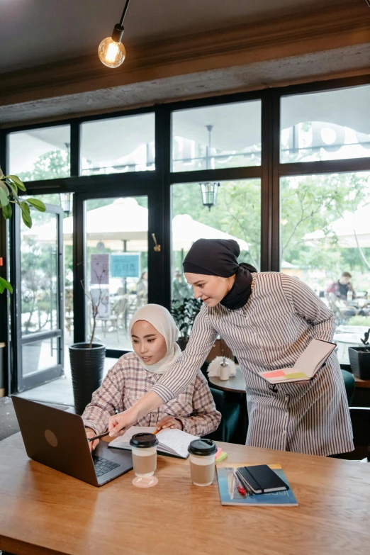 a woman and another woman are using laptops at a coffee shop