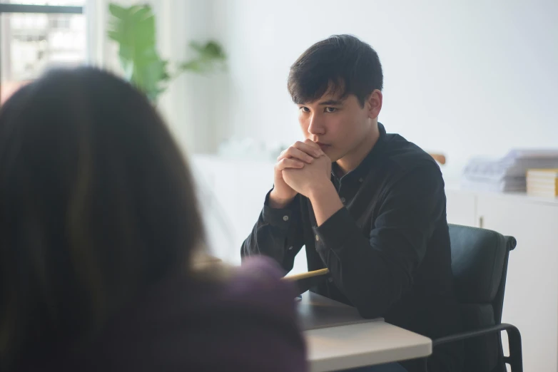 a man sitting at a table in front of another woman