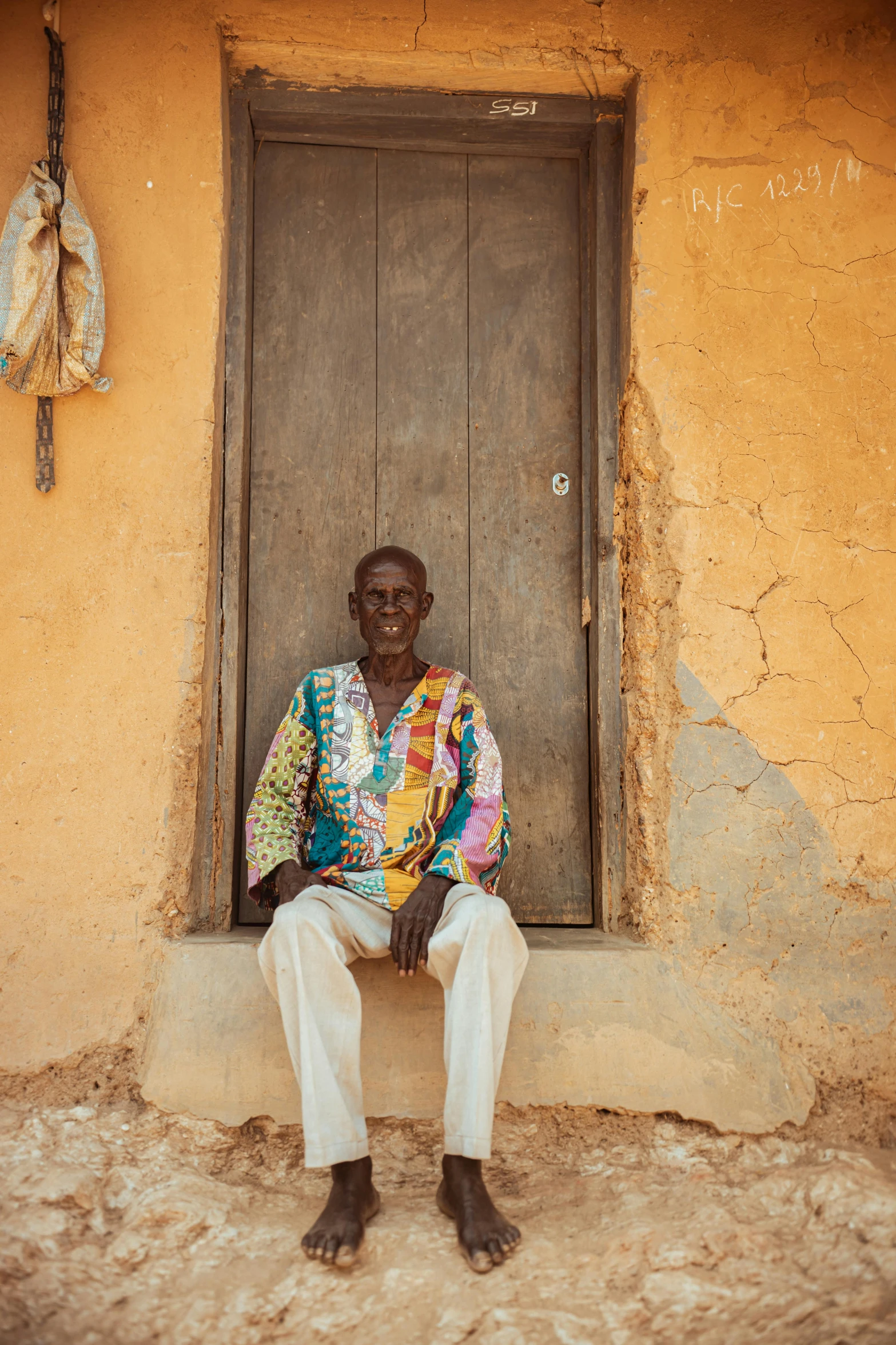 an older man in brightly colored clothing is sitting outside of a window