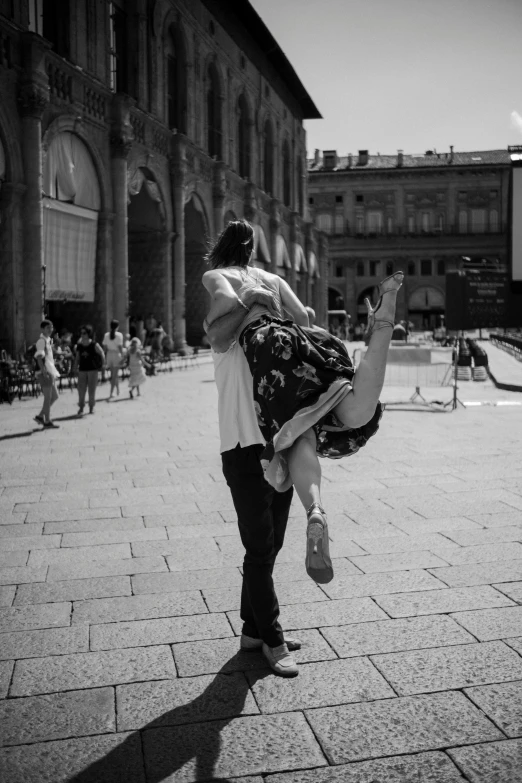 a man carrying a woman across a sidewalk