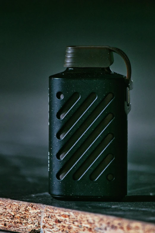 a flask - shaped can is on the surface with the handle extended