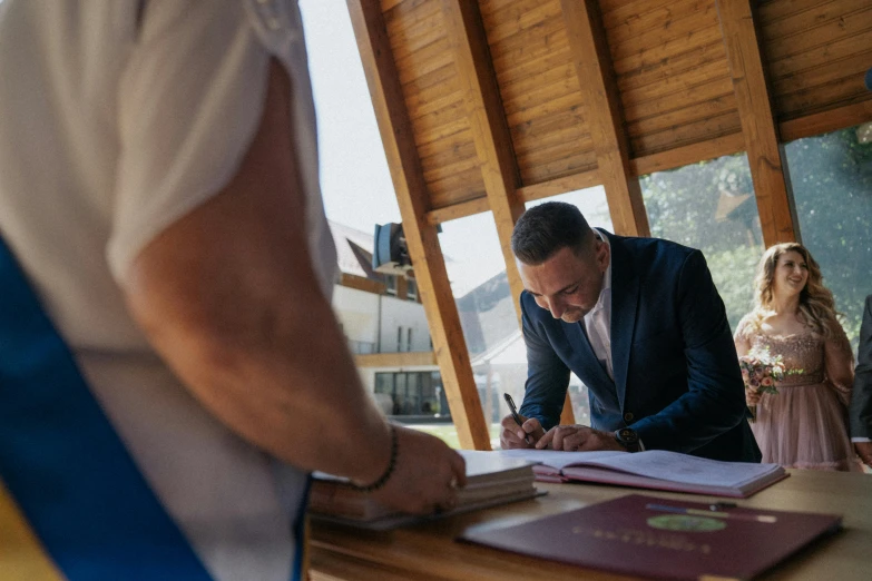 a man signing soing on top of a wooden table