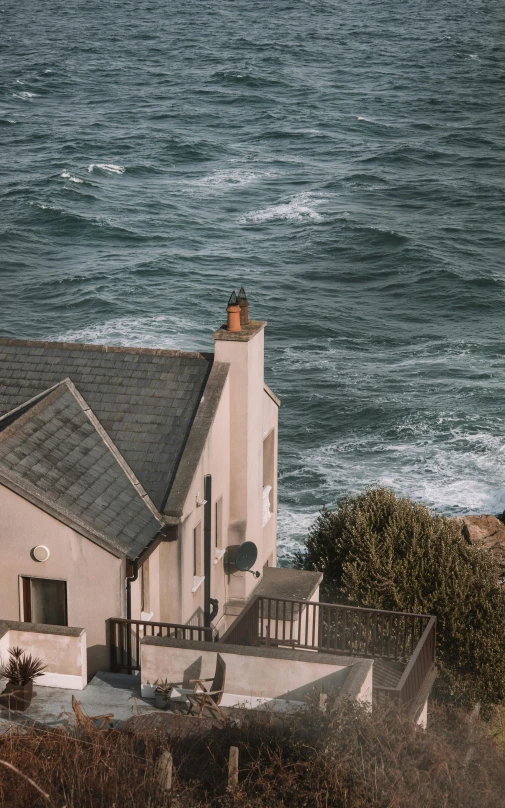 the house is next to an ocean line and has a bird perched on it