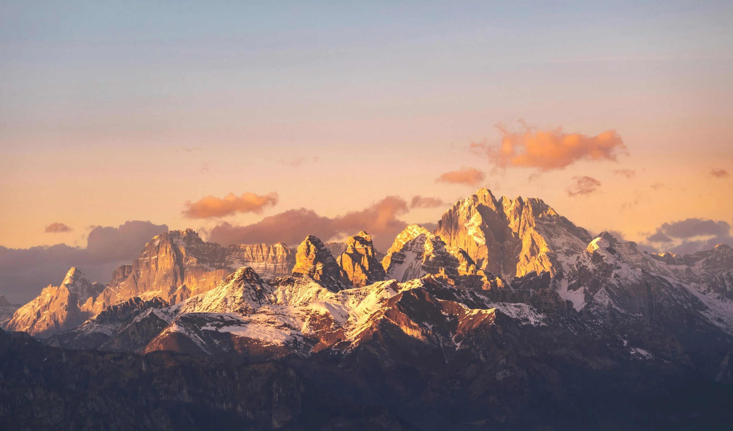 the tops of mountains covered in snow at sunset