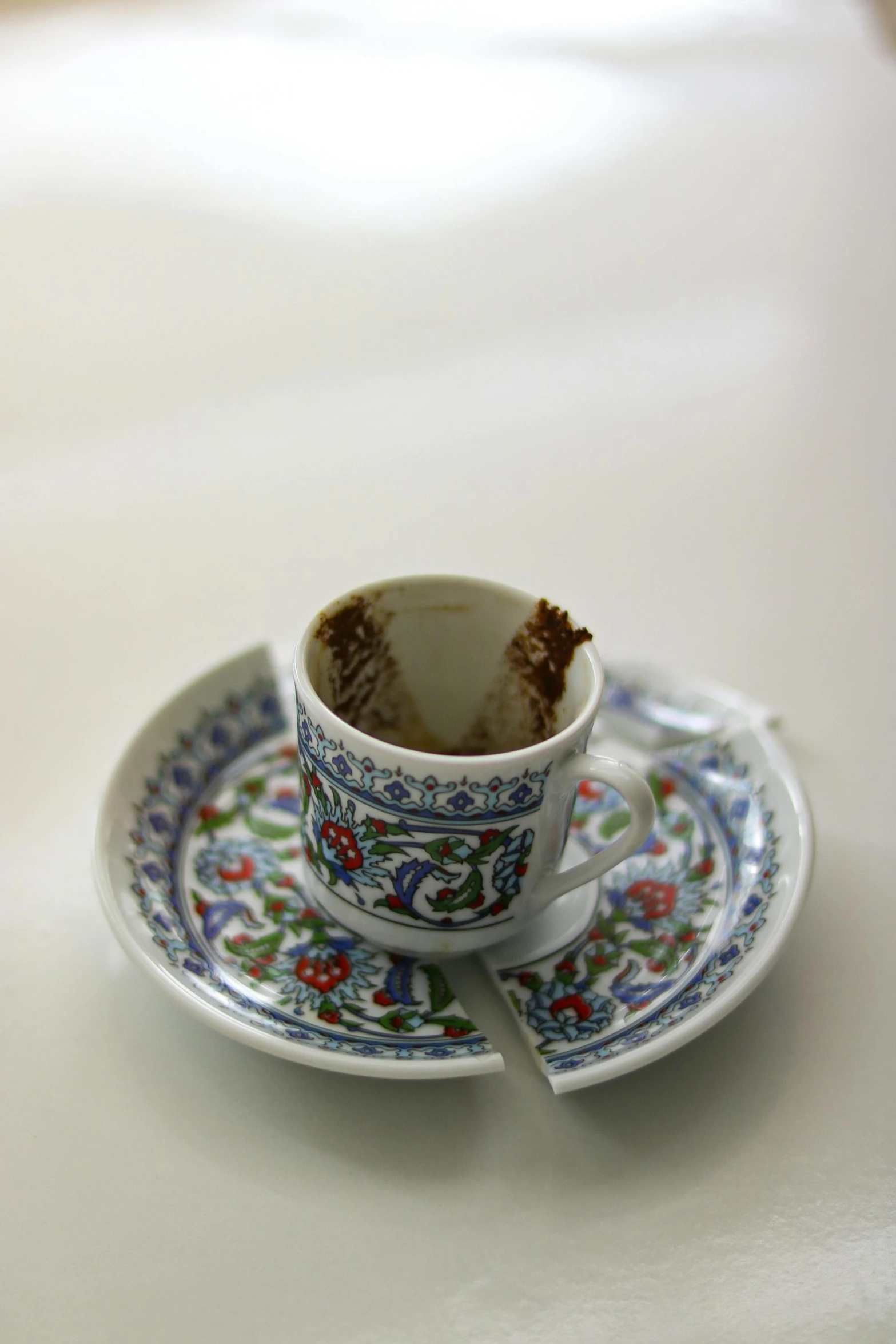 a broken coffee cup sits on top of the plate