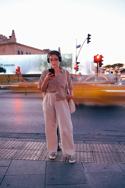 a woman standing on a sidewalk while wearing headphones