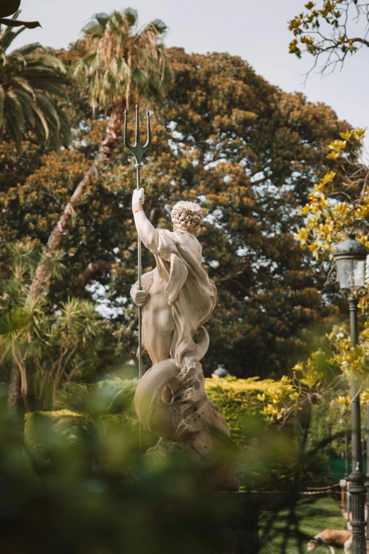 an angel statue holding a garden pitchfork in a courtyard