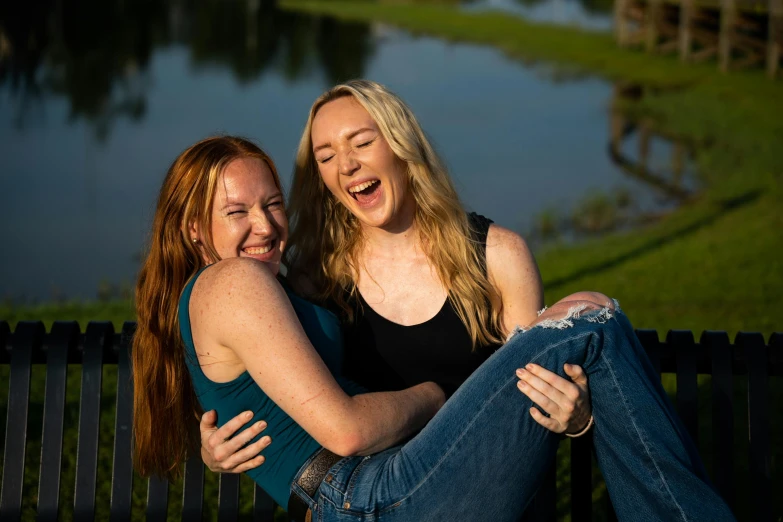 two young beautiful women sitting next to each other on a bench