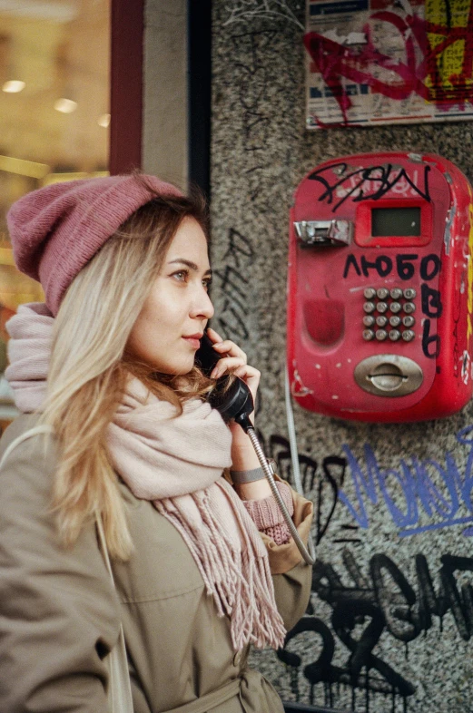 a woman standing next to a wall talking on a cellphone